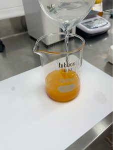 Mediterranean multifruit juice concentrate being diluted with water in laboratory glassware, illustrating clarity and colour during formulation