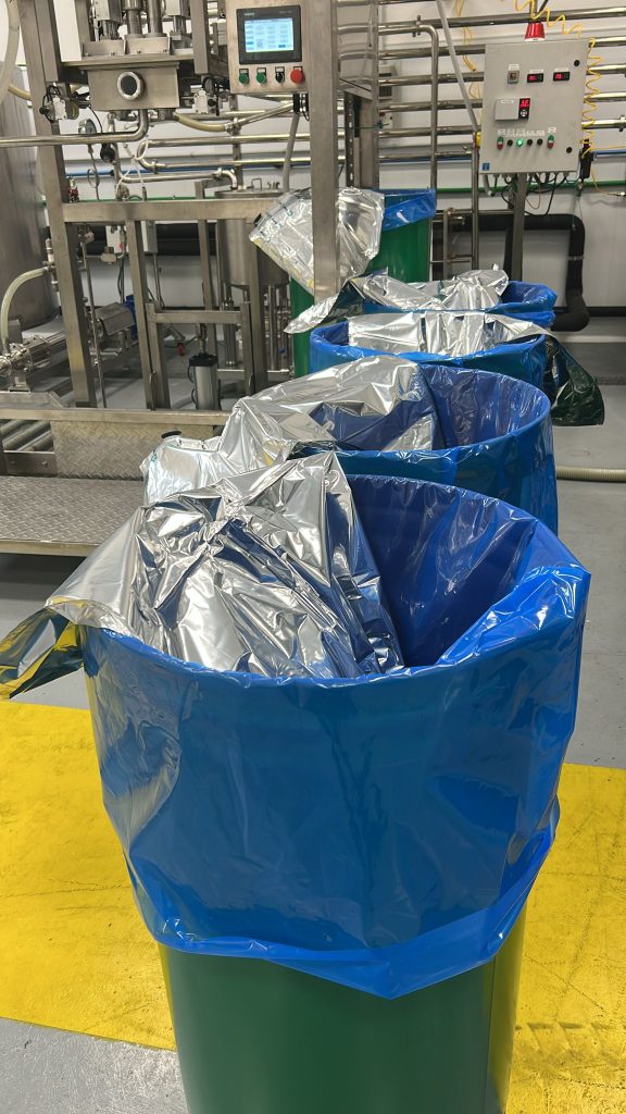 Industrial aseptic fruit concentrate packaging line with bag-in-drum containers prepared for filling in a food processing facility